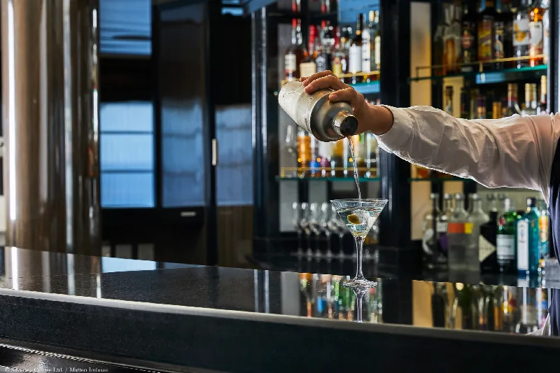 A bartender pouring a martini at the bar of a cruise ship