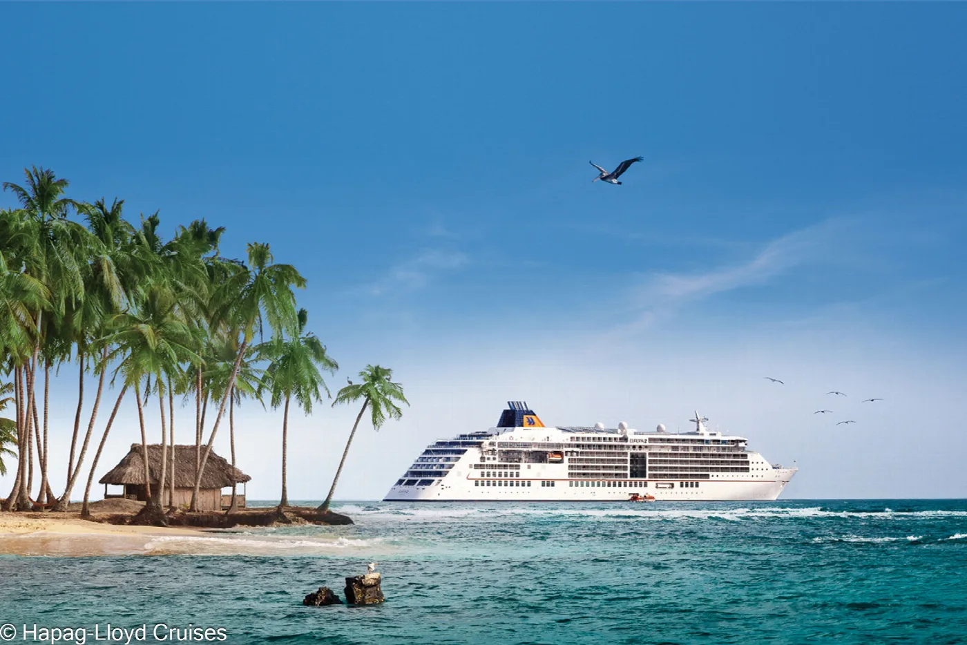 A small cruise ship off a palm island with a thatched hut in San Blas, Panama