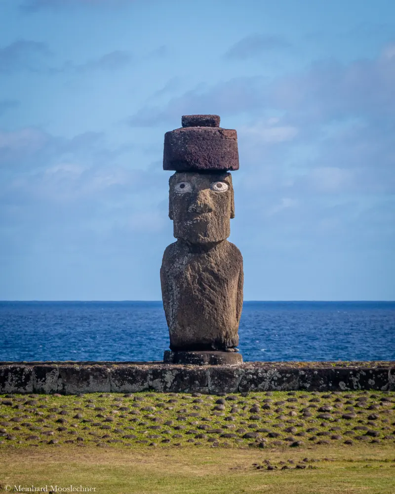 A moai with a red stone topknot on Easter Island, the Pacific behind