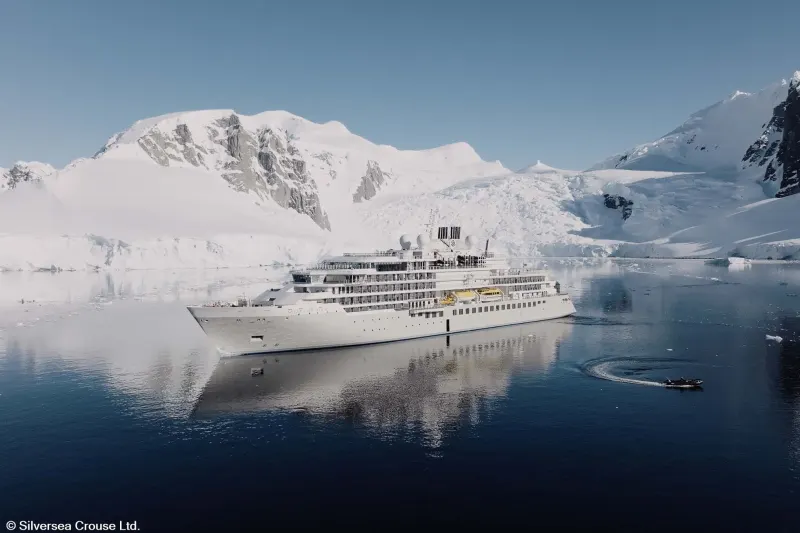 The expedition ship Silver Endeavour of Silversea in a bay below snow-covered Antarctic mountains
